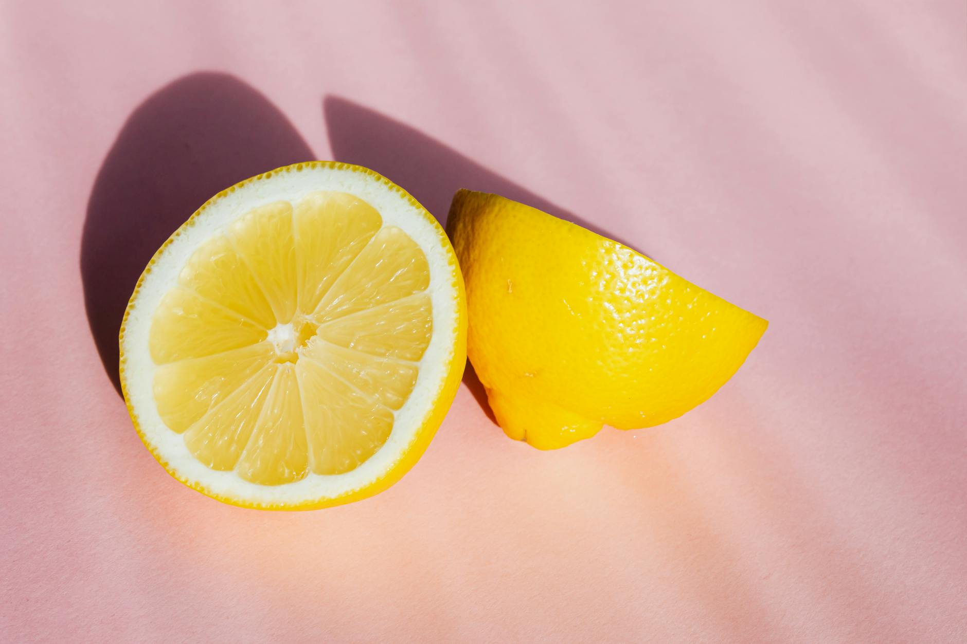 Fresh lemon halves arranged on a pink background, symbolizing renewal and sensitivity restoration