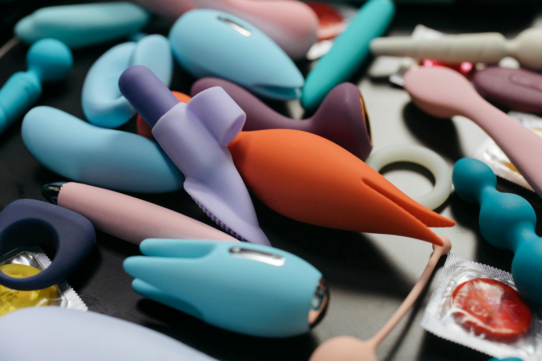 Hand holding a sleek vibrator against a purple background, representing clitoral pleasure tools