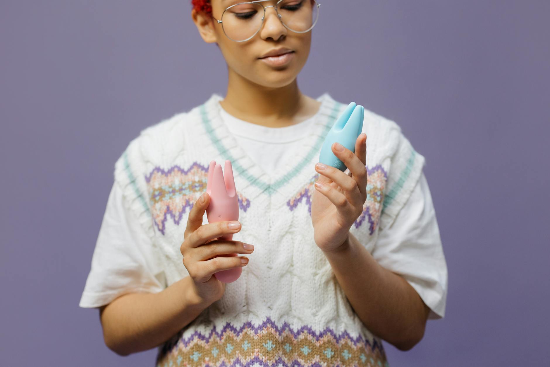 Woman holding a blue silicone vibrator with a thoughtful expression about sensation during partnered sex
